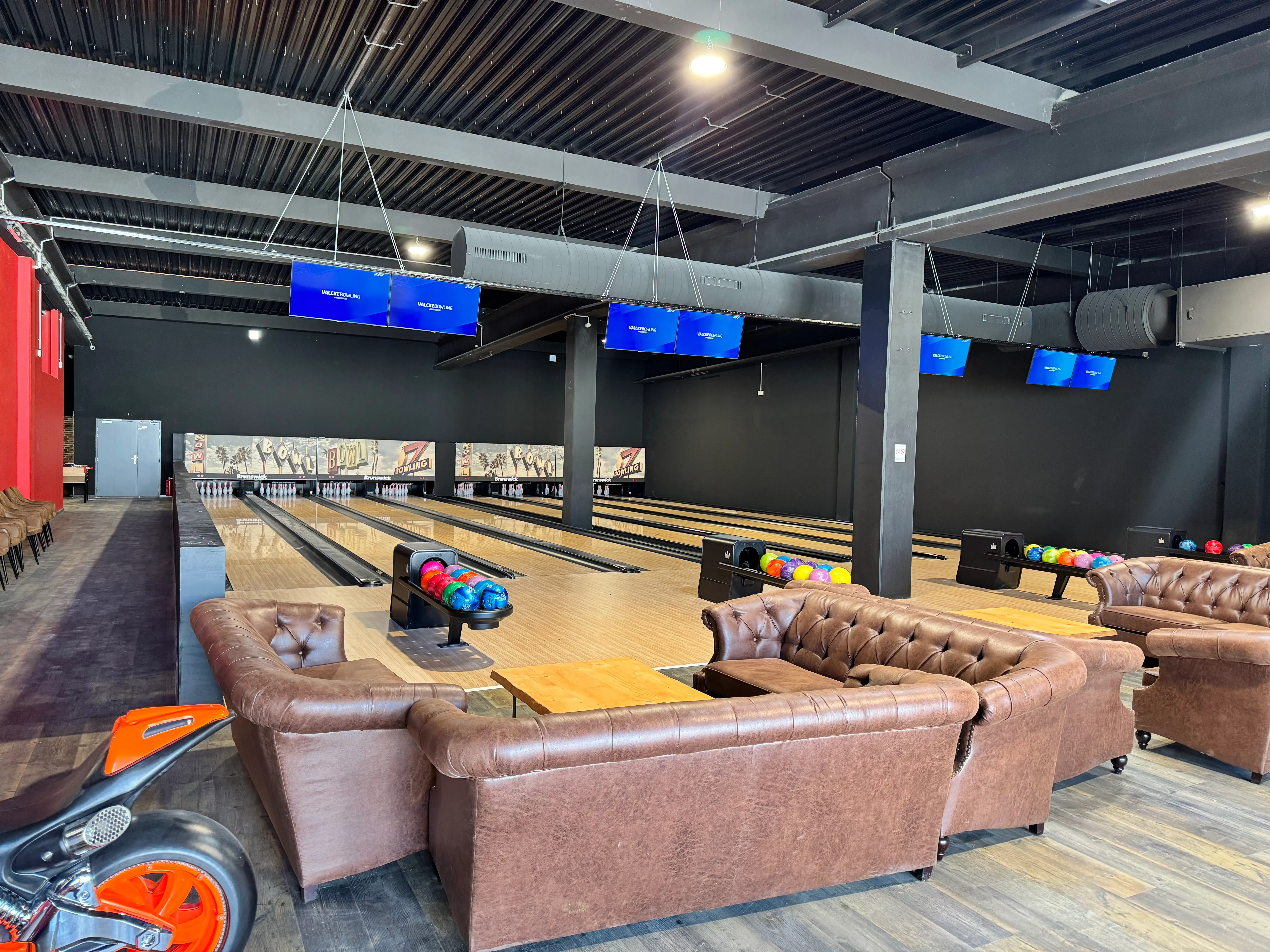 Vue d'ensemble des pistes de bowling chez OumCityGames, éclairées et prêtes pour le jeu, avec des écrans de score numériques en arrière-plan