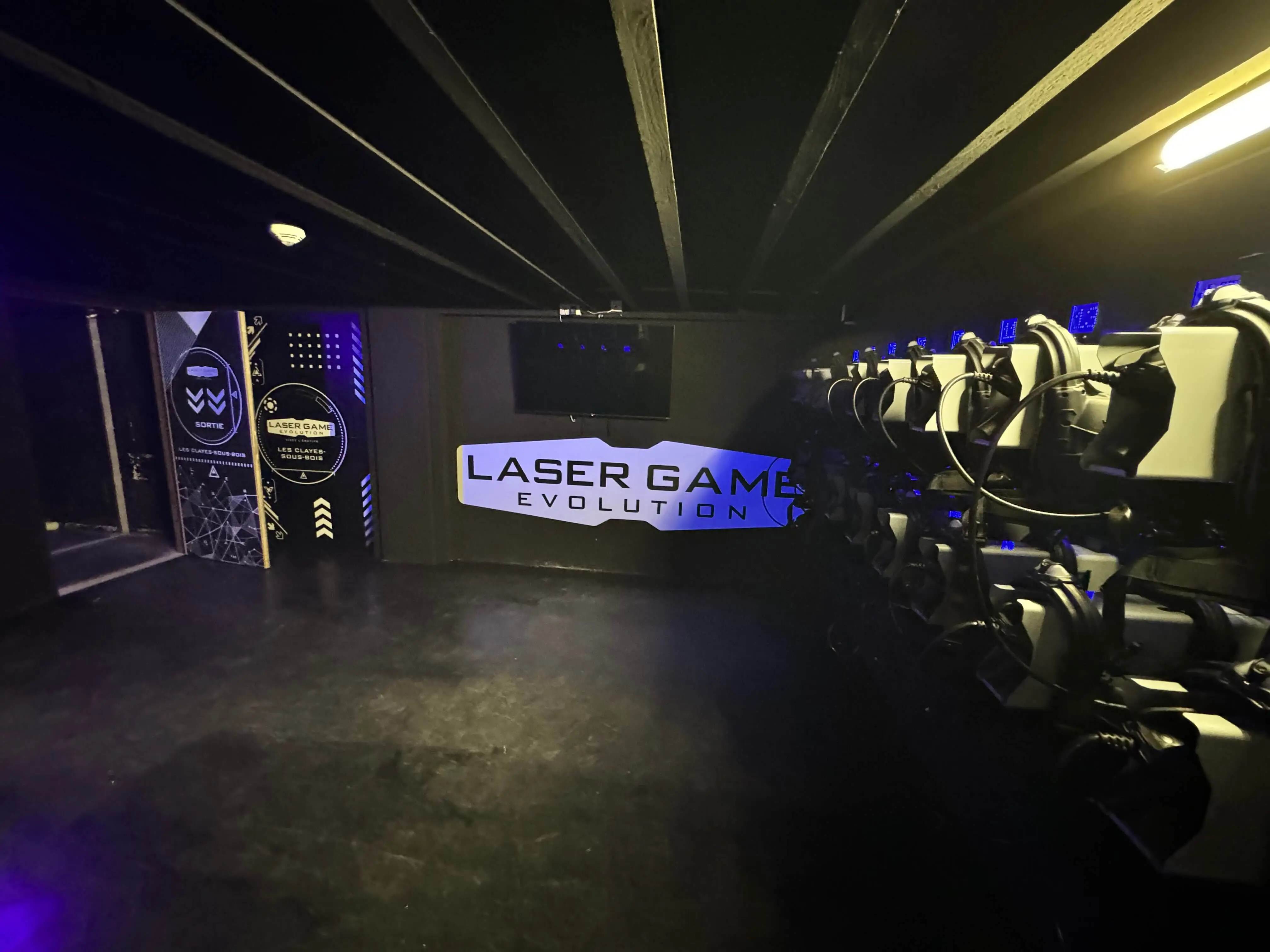 Équipements de Laser Game chez OumCityGames, incluant gilets et pistolets laser sur fond noir éclairé